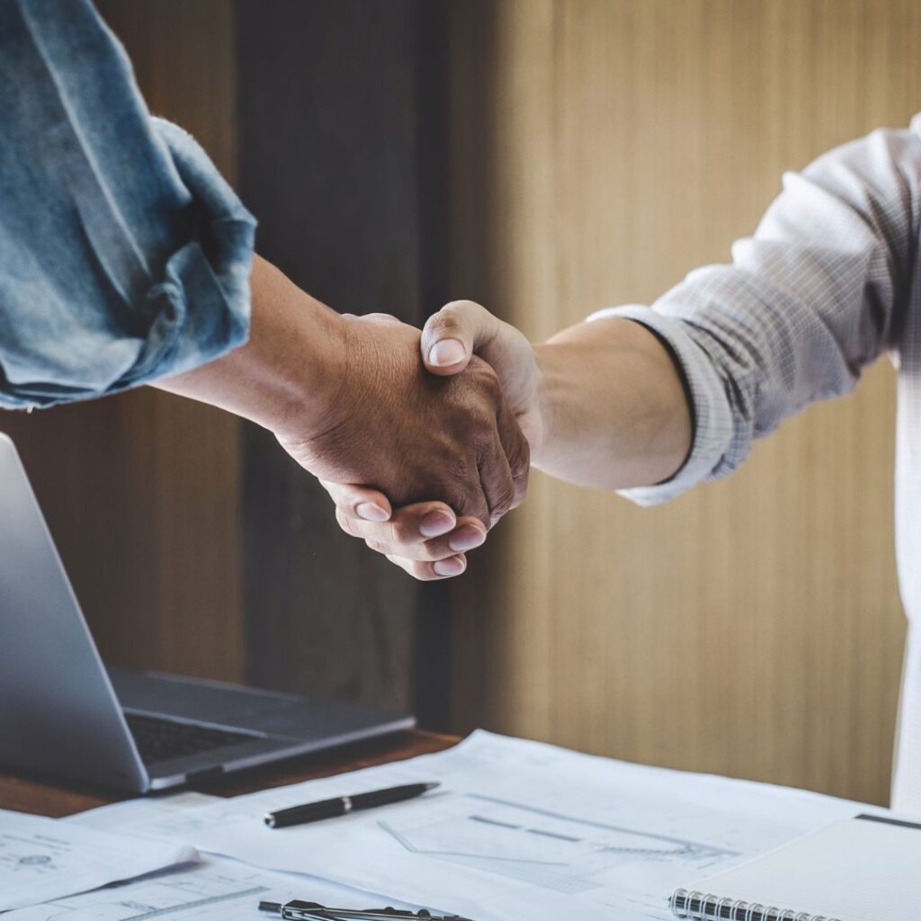 2 people shaking hands over a desk