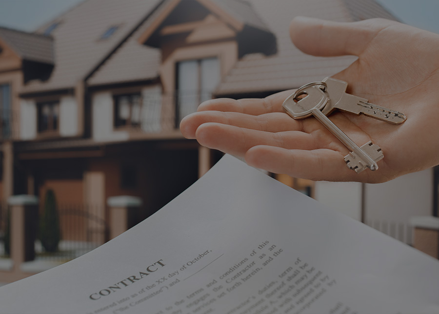 hand holding keys in front of a house