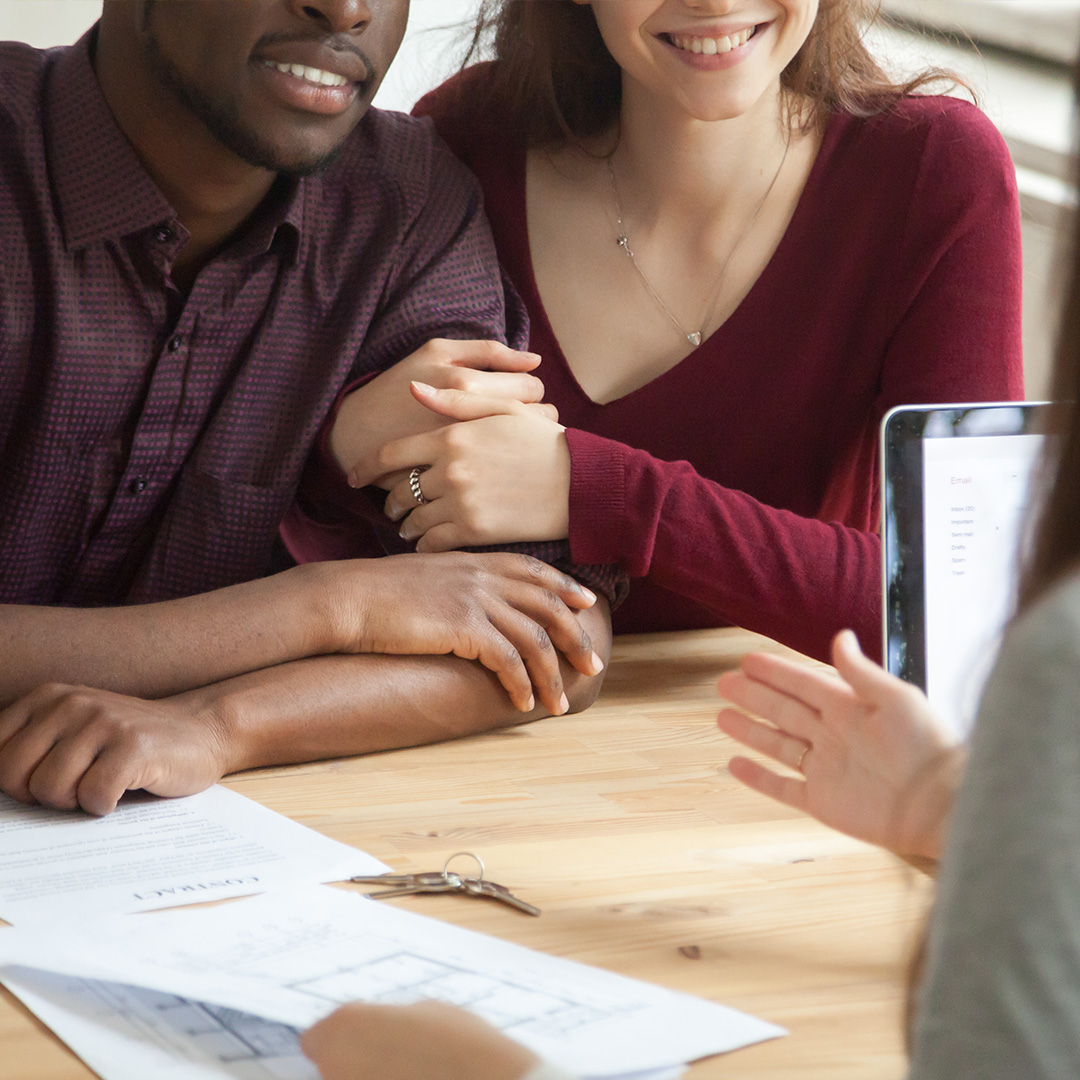 excited couple with keys in front of them on table
