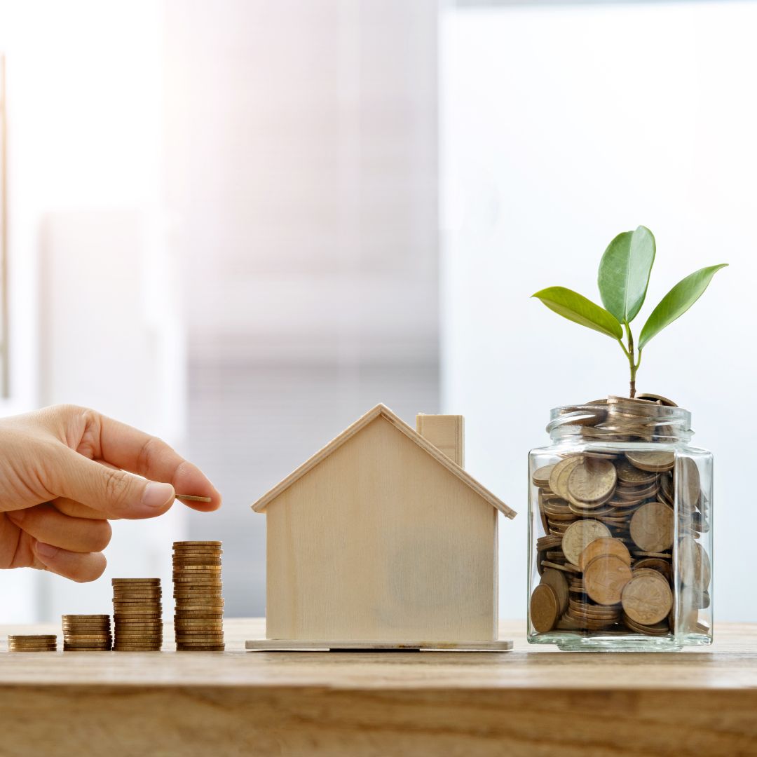 stacking coins next to small wooden house